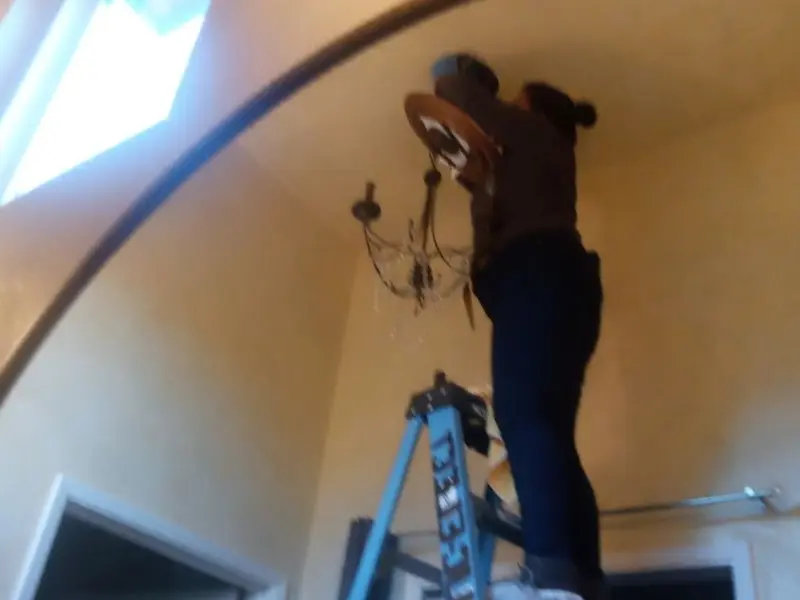 Electrician installing a chandelier in a Durant residence